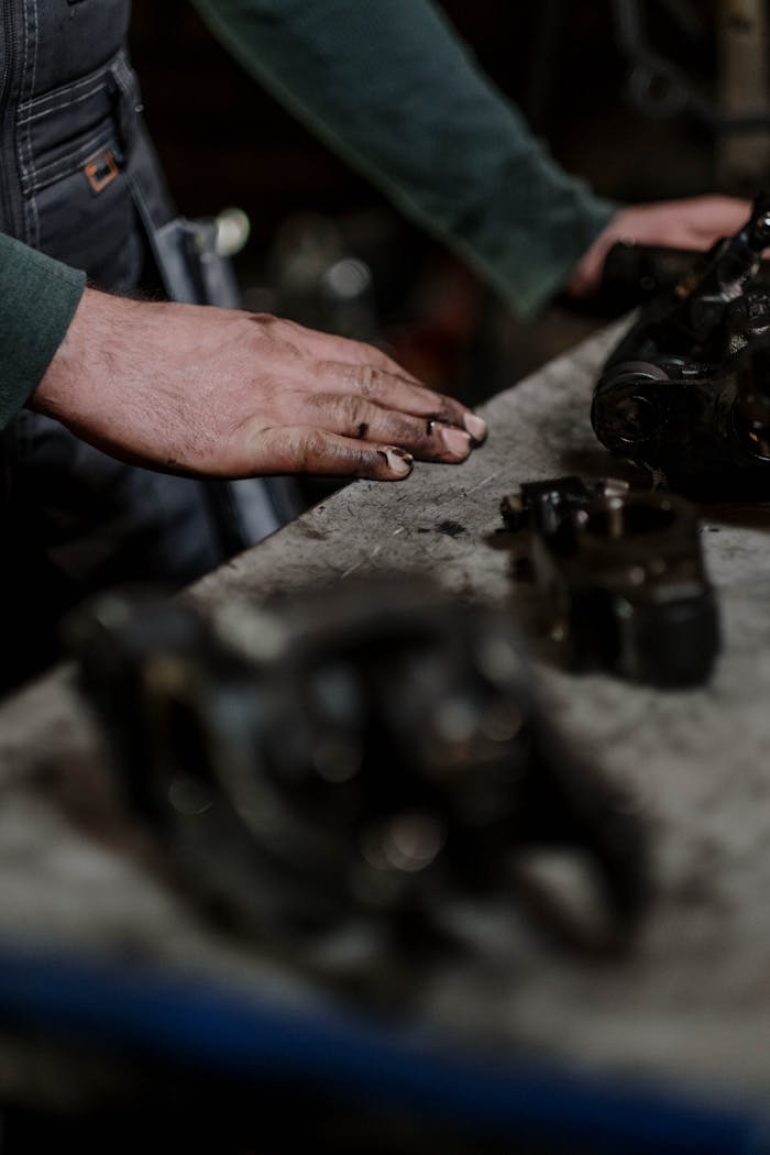 our-story Close-up of a mechanic's hands inspecting engine parts in a workshop setting.