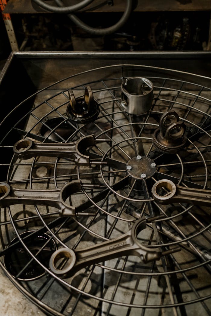 Close-up view of car parts arranged on a metal grid in a garage setting highlighting industrial details.
