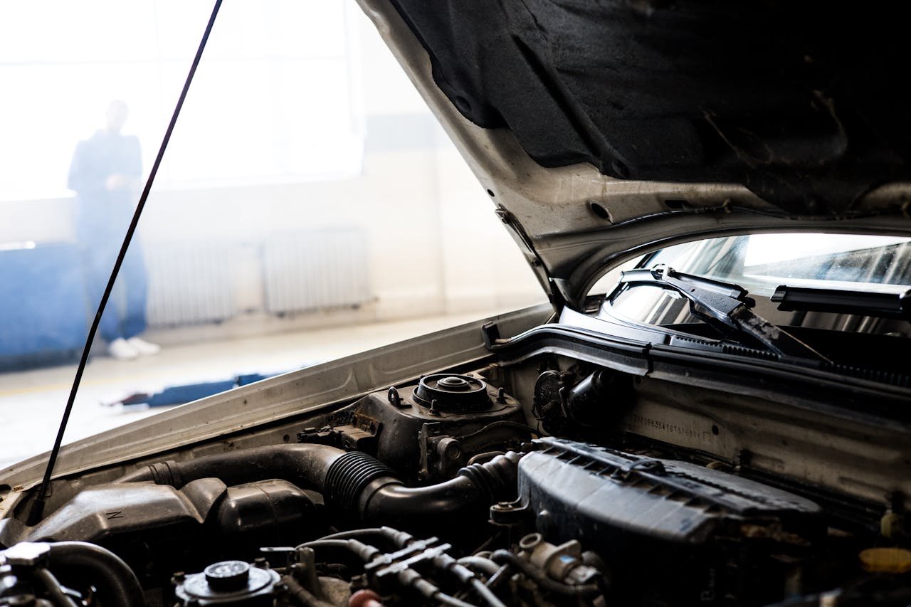 about-us Detailed image of a car engine underneath the open hood in a well-lit indoor garage.